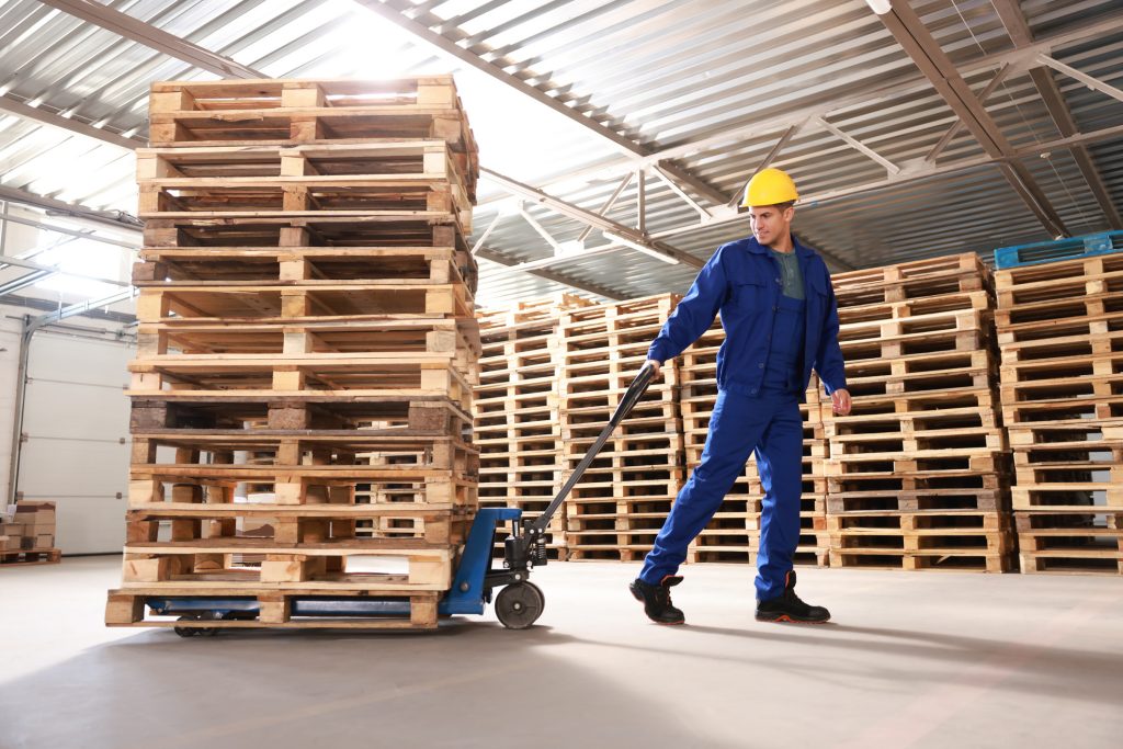 Worker pulling pallet stack safely.